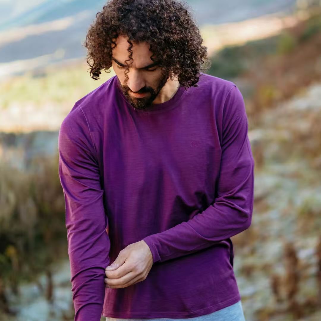 Man wearing ZEALWOOD purple merino long-sleeve T-shirt on a mountain trail